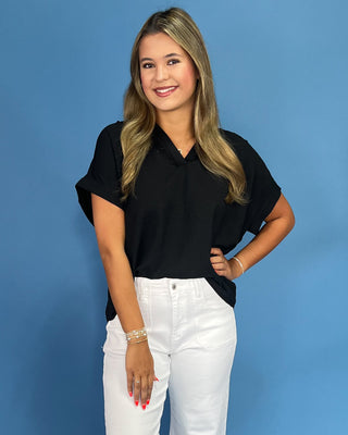 Woman wearing a black shirt and white pants against a blue background