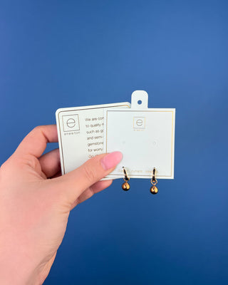 Shop the Enewton Huggie Hoop Gold Charm Earrings featuring polished gold hoops and dangling gold ball charms for timeless everyday style.