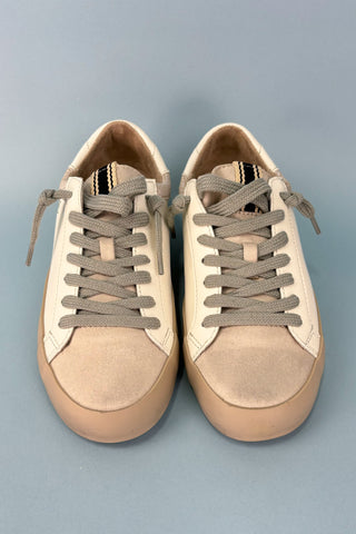 Pair of beige sneakers with brown laces on a gray background