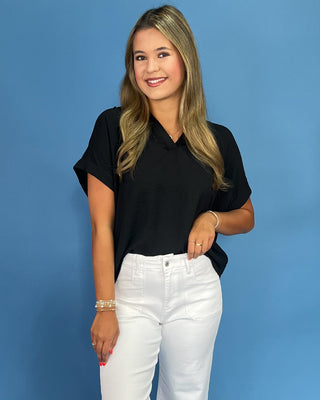 Woman wearing a black shirt and white pants against a blue background