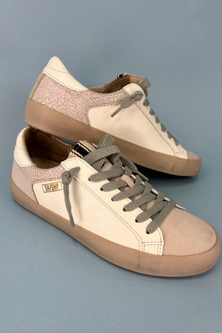 Pair of beige and brown sneakers on a gray background