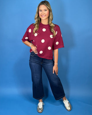Burgundy short sleeve knit sweater top with oversized ivory polka dots, a round neckline, and ribbed trim.