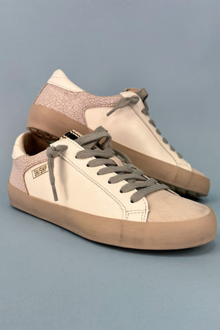 Pair of beige and brown sneakers on a gray background