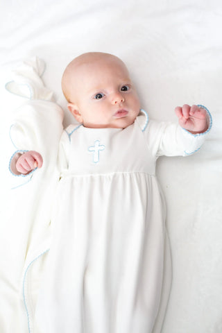 Baby in a white gown with a cross design on a white background