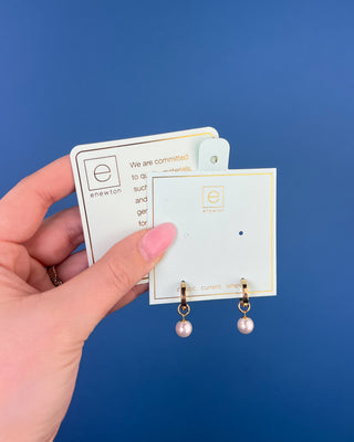 Shop the Enewton Huggie Hoop Pearl Charm Earrings featuring polished gold hoops and elegant dangling white pearl charms for timeless everyday style.