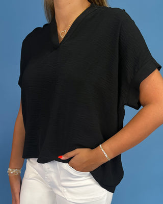 Person wearing a black top and white pants against a blue background