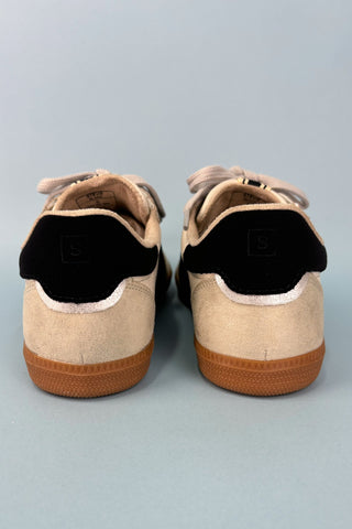 Pair of beige sneakers with brown soles on a light gray background