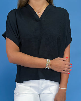 Person wearing a black top and white pants against a blue background