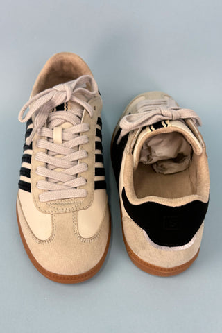 Pair of beige and black sneakers on a light gray background