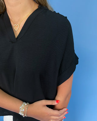 Person wearing a black top with a blue background