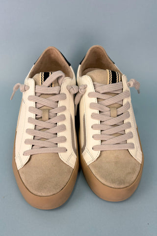 Pair of tan sneakers with brown soles on a gray background