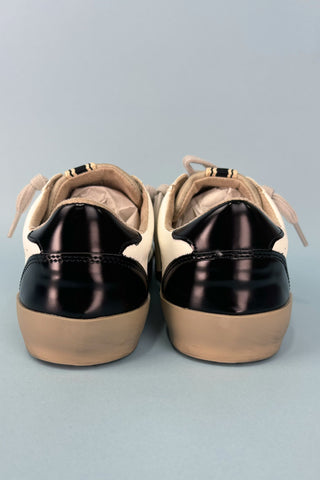 Pair of tan and black sneakers on a gray background