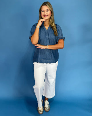 Woman wearing a blue top and white pants against a blue background