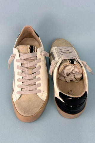 Pair of beige sneakers with brown soles on a gray background