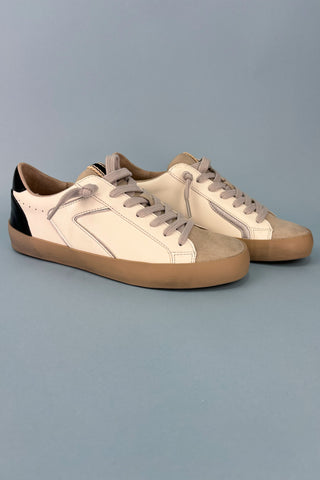 Pair of beige sneakers with brown soles on a gray background