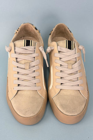 Pair of beige sneakers with white laces on a gray background