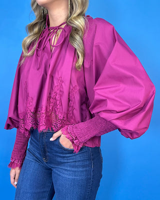 Magenta lace trim blouse with dramatic balloon sleeves, smocked cuffs, and a feminine tie-neck detail.