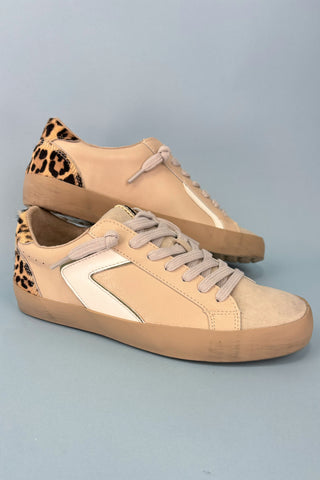Beige sneakers with leopard print accents on a gray background