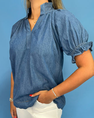 Woman wearing a blue denim blouse against a blue background