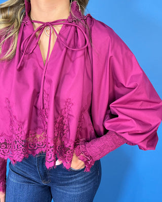 Magenta lace trim blouse with dramatic balloon sleeves, smocked cuffs, and a feminine tie-neck detail.