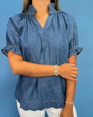 Woman wearing a blue denim blouse against a blue background