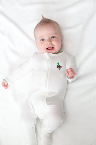 Baby wearing a white onesie with a small design on a white background