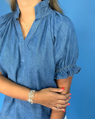 Person wearing a blue denim shirt against a blue background