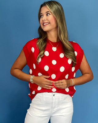 Woman wearing a red polka dot top against a blue background