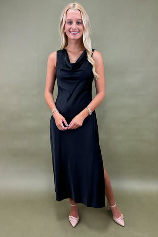 Woman wearing a black sleeveless dress against a plain background