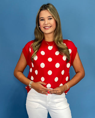 Woman wearing a red polka dot shirt against a blue background