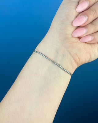 Shop the Enewton Hope Classic Signature Cross Morning Mist Bracelet featuring iridescent gray glass beads and a delicate gold cross charm.