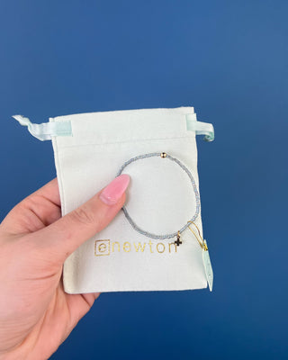 Shop the Enewton Hope Classic Signature Cross Morning Mist Bracelet featuring iridescent gray glass beads and a delicate gold cross charm.