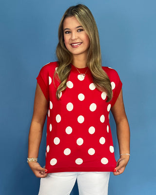 Woman wearing a red polka dot shirt against a blue background