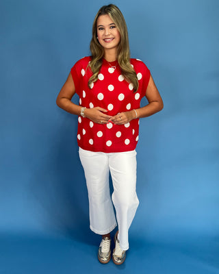 Woman wearing a red polka dot shirt and white pants on a blue background