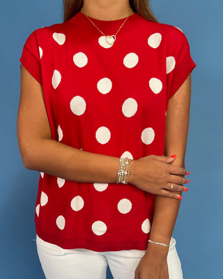 Person wearing a red polka dot top against a blue background