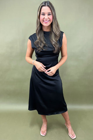 Woman wearing a black dress against a green background