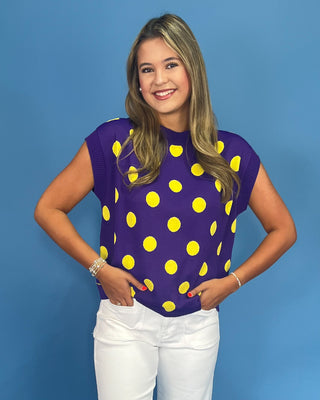 Woman wearing a purple top with yellow polka dots against a blue background