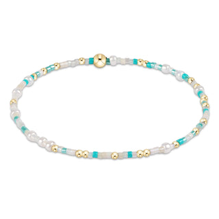 Bracelet with white, turquoise, and gold beads on a white background