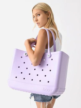 Woman holding a lavender tote bag with black dots on a white background