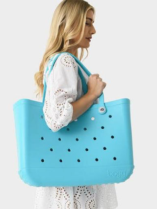 Woman holding a blue tote bag with black dots on a white background