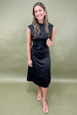 Woman wearing a black dress against a plain background
