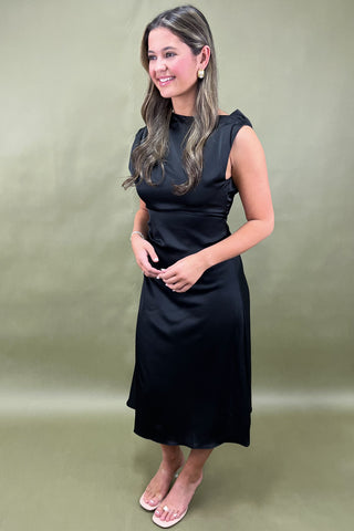 Woman wearing a black dress against a plain background