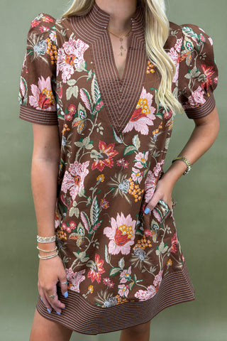 Woman wearing a brown floral dress against a green background