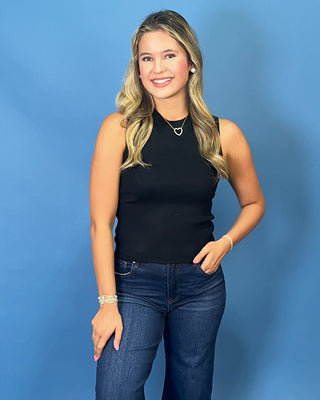 A woman with blonde hair stands against a solid blue background