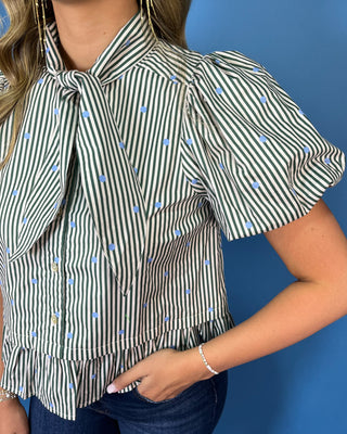 Ivory and black striped puff sleeve blouse with light blue polka dots, a statement tie neckline, button front, and ruffle hem.