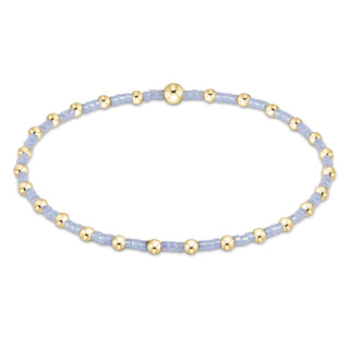 Bracelet with gold beads on a light blue string against a white background