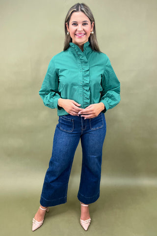 Woman wearing a green blouse and blue jeans against a green background