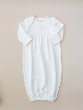 White baby gown with pink cross on a beige background