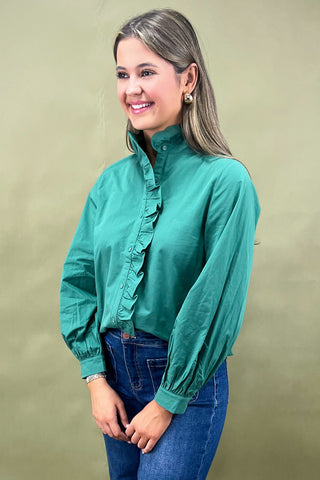 Woman wearing a denim dress with ruffled sleeves against a light blue background