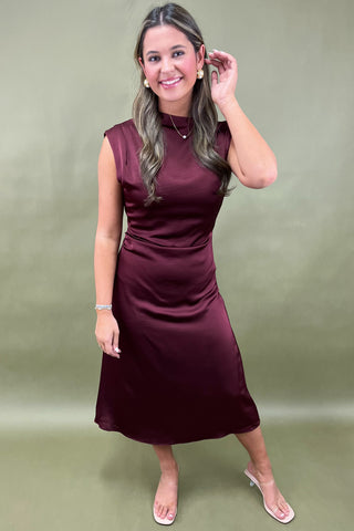 Woman wearing a burgundy dress against a green background